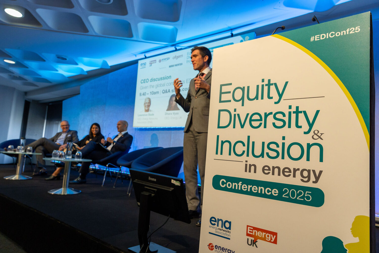 A British Sign Language interpreter stands next to a panel of industry leaders at the Equity, Diversity and Inclusion in Energy Conference 2025