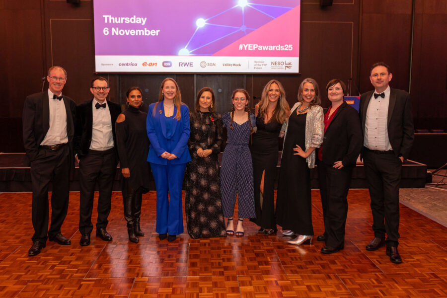 A group of attendees dressed in formal evening wear stand together on a stage, posing for a photo beneath a screen showing ‘Energy UK YEP Awards 2025’ and ‘Thursday 6 November’, with sponsor logos visible.